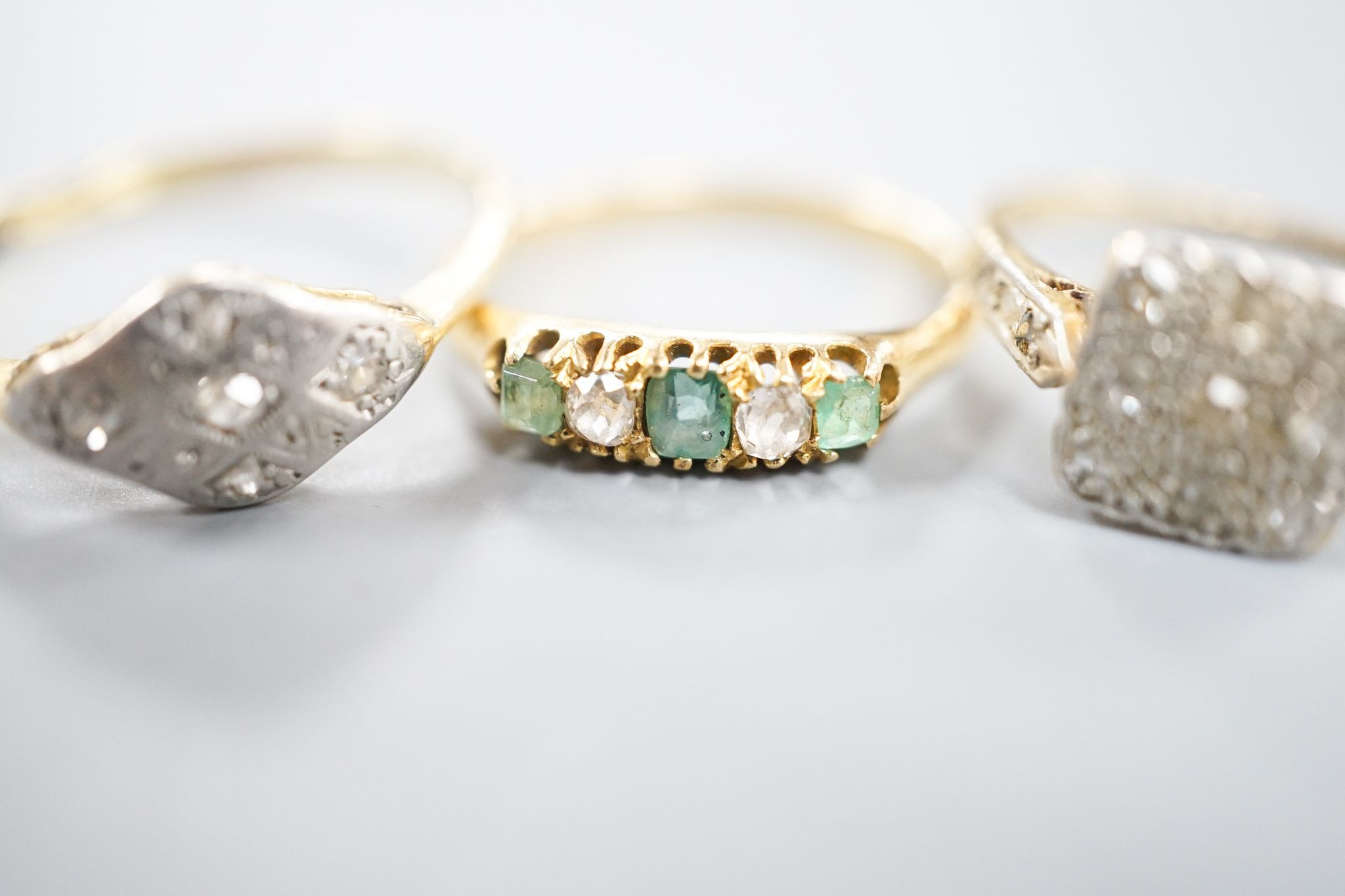 Two 18ct, plat. and diamond chip set dress rings and an 18ct, emerald and diamond set five stone ring, sizes P,I and H/I, gross weight 6 grams.